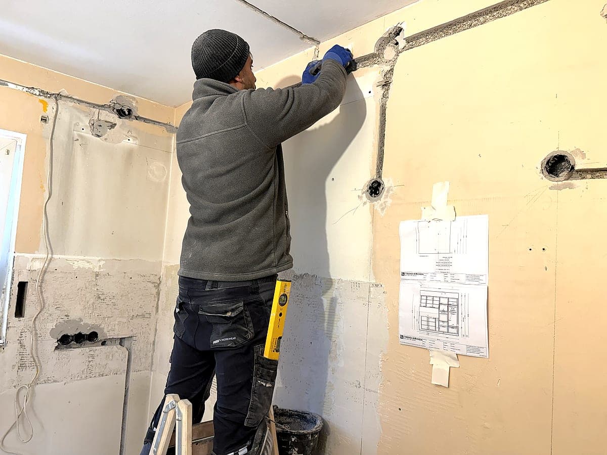 TESHGE Team bei der Arbeit – Elektriker auf Leiter bei Kücheninstallation